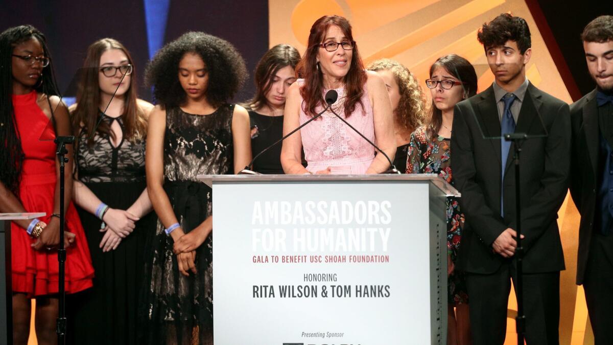 Teacher Ivy Schamis, center, speaks onstage during the Ambassadors for Humanity gala.