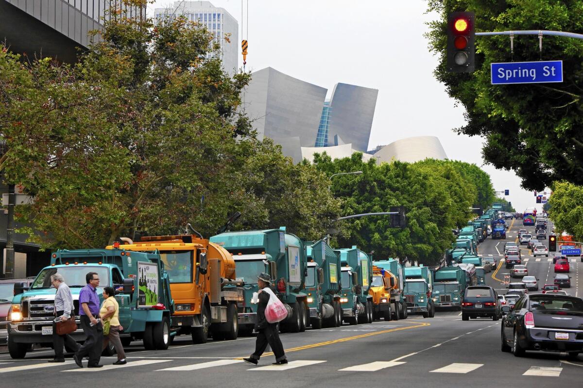 A line of garbage trucks drive in a convoy on 1st Street on their way to Los Angeles City Hall on Tuesday morning, protesting what some call "predatory fees" the city pays to Wall Street banks.