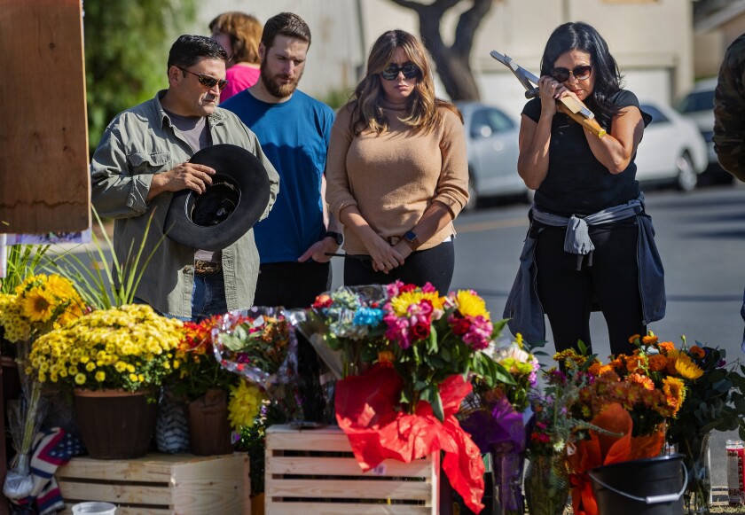 Rosie Ritchie, right, holds a cross while standing with mourners at a memorial near where Joseph Awaida, his toddler son and his wife, Raihan, were struck by a suspected DUI motorist on Halloween.
