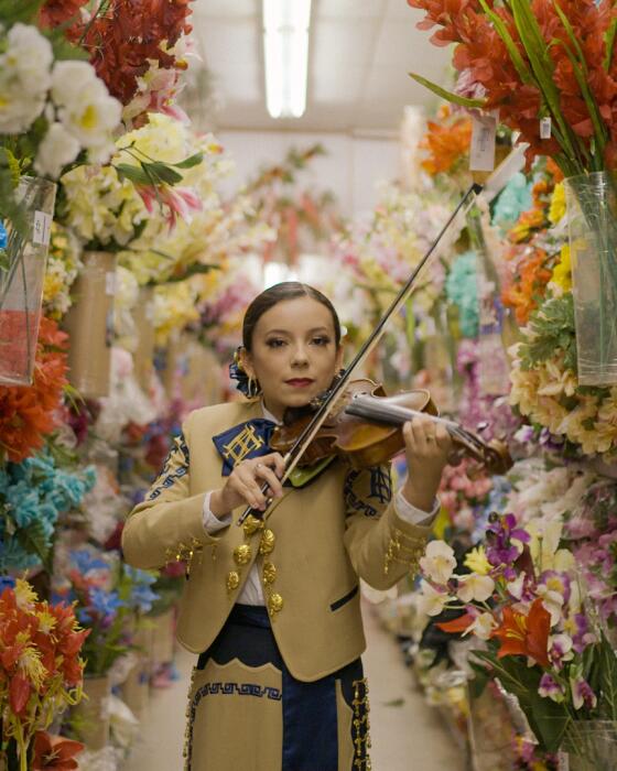 A woman mariachi plays a violin 