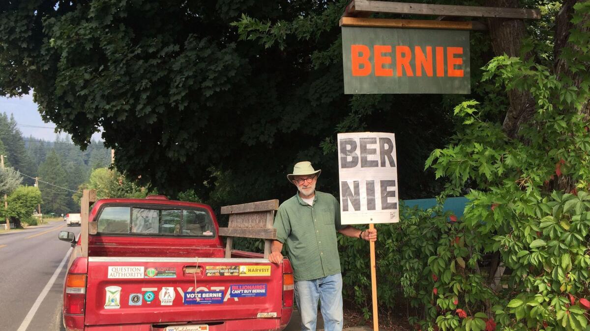 Wayne Cartwright, 70, stands with his homemade Bernie Sanders sign and his pickup truck covered in progressive-themed bumper stickers outside his house in Quincy.