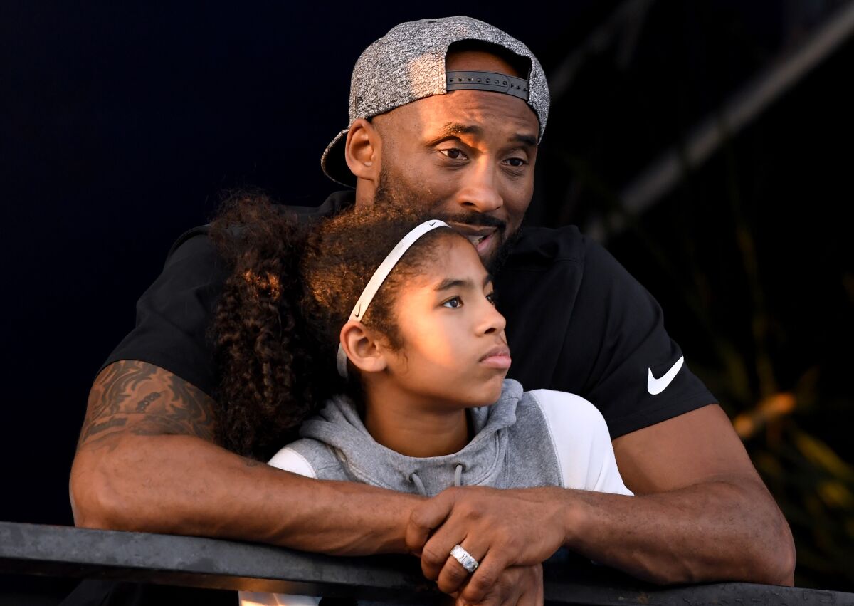 Lakers legend Kobe Bryant hugs his daughter Gianna as they watch the National Swimming Championships.