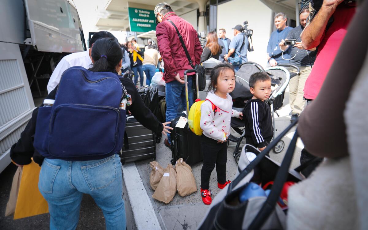 Un grupo de evacuados de China que huyen del coronavirus, y que han completado la cuarentena de 14 días en el MCAS Miramar, se bajan de un autobús chárter en el Aeropuerto Internacional de San Diego, el 20 de febrero de 2020,