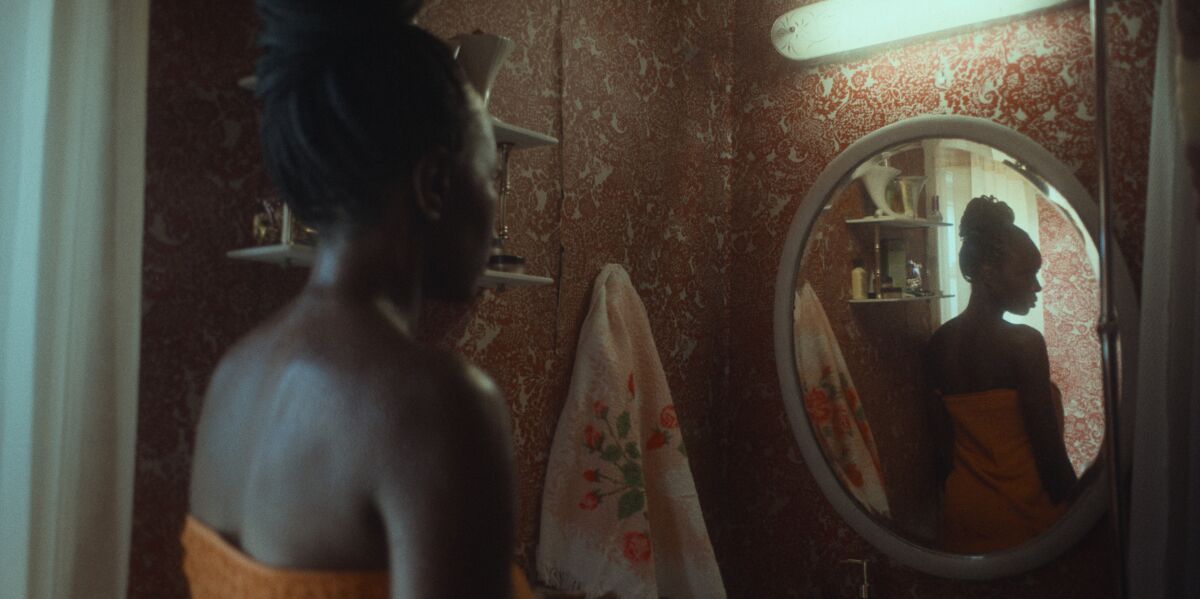 A woman in a towel in a bathroom mirror