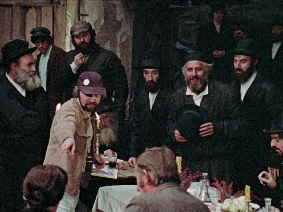 A movie director points as the cast watches on the set of "Fiddler on the Roof.”