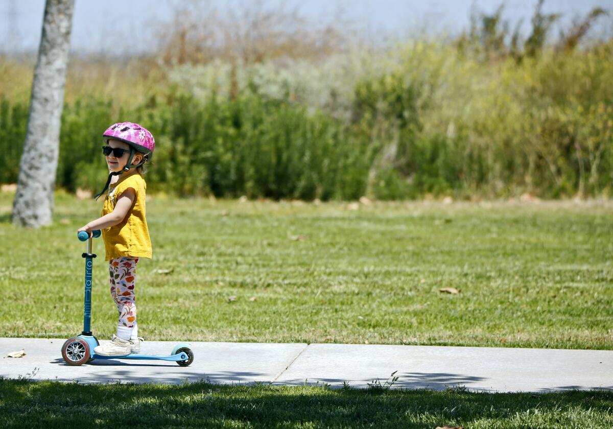 Olive Rogers, 3, from Orange, rides her scooter with her parents just behind her at Fairview Park in Costa Mesa on Saturday.