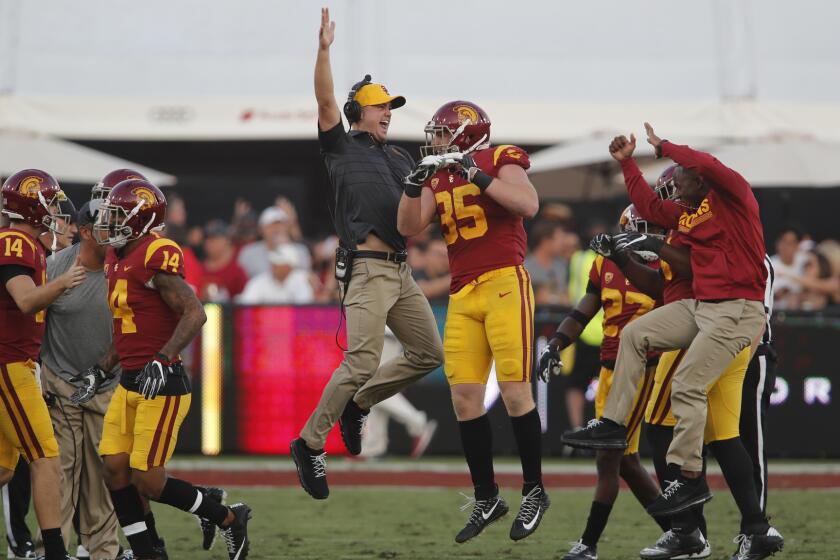 USC linebacker Cameron Smith (35) celebrates with his coaches after picking off a Troy Williams pass in the first quarter of a game at the Coliseum.