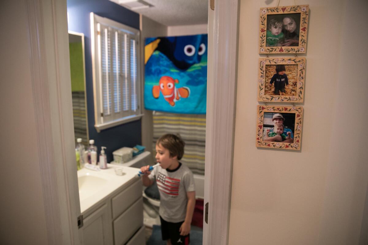 Ashton gets ready for school. Pictures of his mother hang in the hallway.