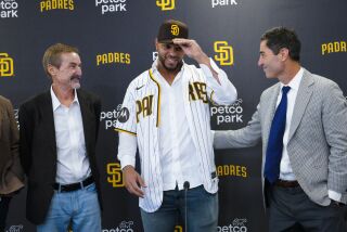 San Diego, CA - December 09: At press conference held at Petco Park on Friday, Dec. 9, 2022 in San Diego, CA., Xander Bogaerts tries on his Padres jersey and cap with Peter Seidler (l) and A. J. Preller (r) looking on. (Nelvin C. Cepeda / The San Diego Union-Tribune)