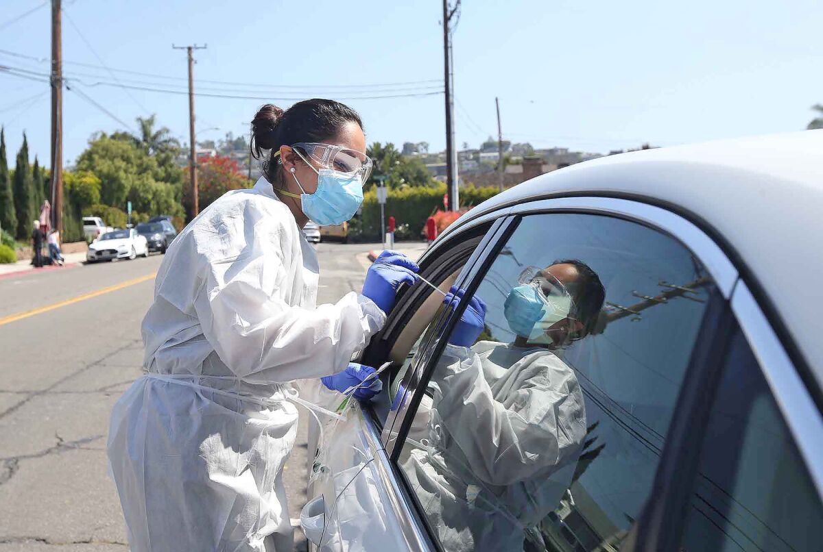 Assistant Janet Muratalla administers a drive-up coronavirus swab test at the Caduceus Medical Group in Laguna Beach on April 14.
