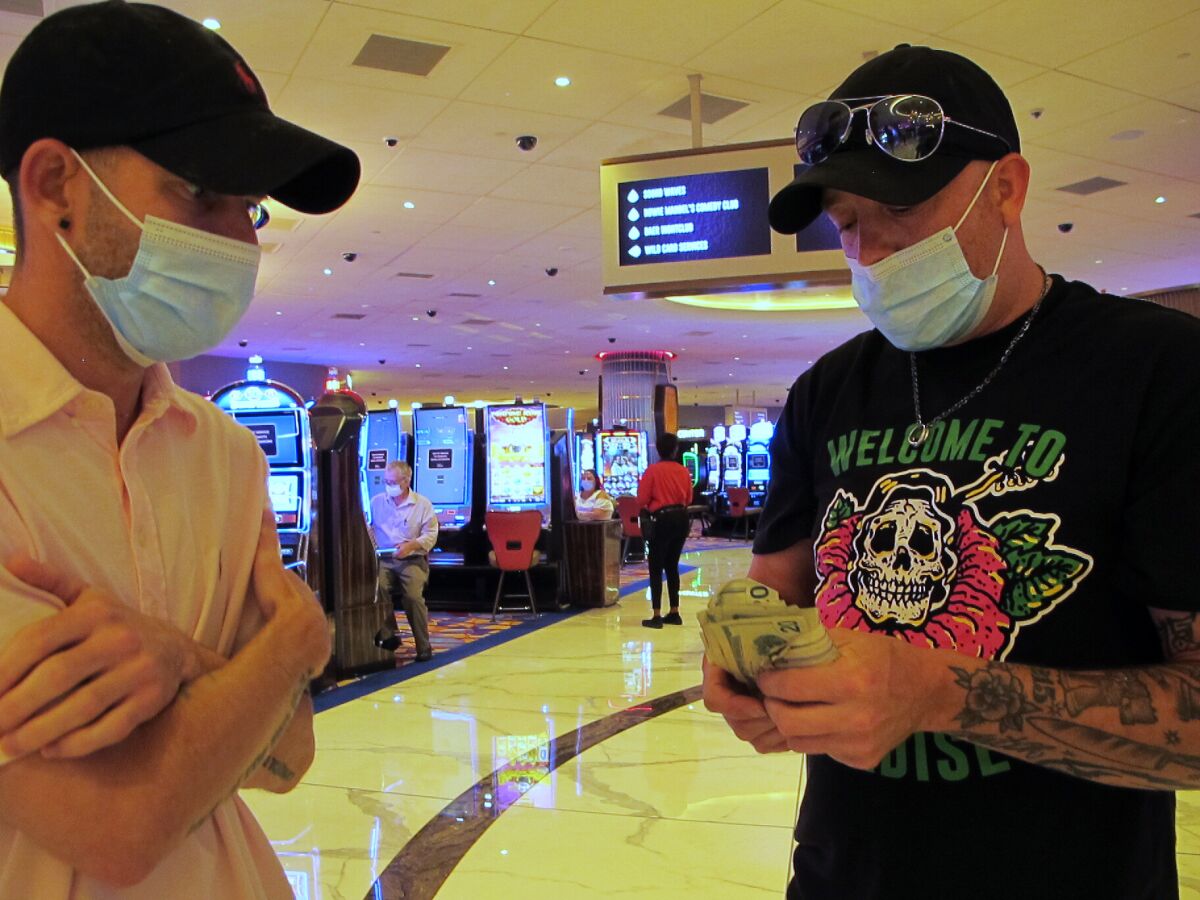 Gamblers count their money before starting to make bets at the Hard Rock casino in Atlantic City, N.J., on July 2, 2020, the day it reopened after being closed for just over three months due to the coronavirus outbreak. New Jersey's casinos and horse tracks won $2.88 billion in 2020, a decrease of nearly 17% from 2019, according to figures released Wednesday, Jan. 13, 2021, by the New Jersey Division of Gaming Enforcement. (AP Photo/Wayne Parry)