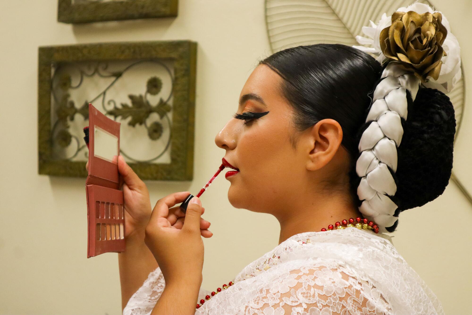 A woman touches up her red lipstick 