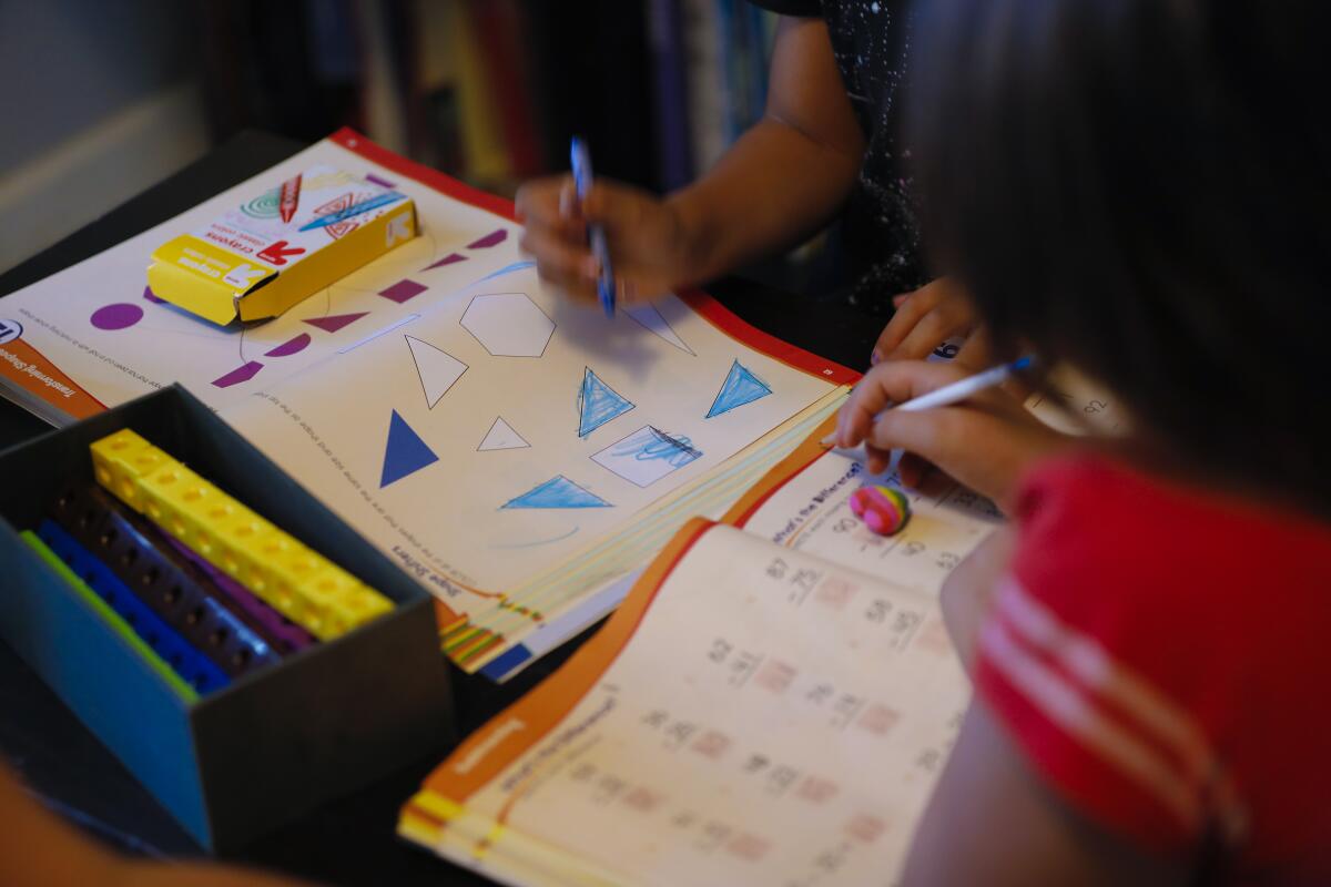 At their home in Chula Vista, Amelia, 6, and Esperanza, 8, work on their home school assignments.