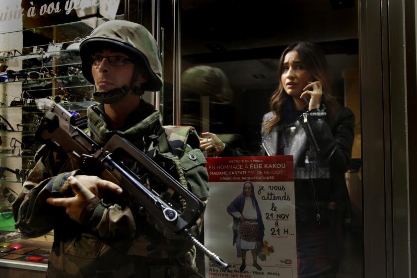 A shopkeeper stays inside her shop as soldiers guard the street where she works.