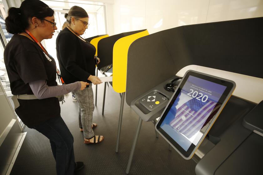 LOS ANGELES, CA - FEBRUARY 27, 2020 Maral Karaccusian, right, is assisted by election assistant Andrea Delgado as she casts her vote at the Mobile Vote Center assembled in Grand Park as the Los Angeles County Registrar-Recorder/County Clerk is trying to provide voters who live and work in downtown with the opportunity to vote in-person in the 12-acre park through 6 p.m. on Thursday. This is part of the county's transition from polling places to vote centers as residents are able to vote at any vote center and are no longer assigned to a specific polling location for in-person voting. (Al Seib / Los Angeles Times)