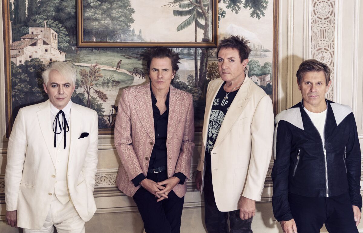  Duran Duran in swanky jackets standing in front of a painting.