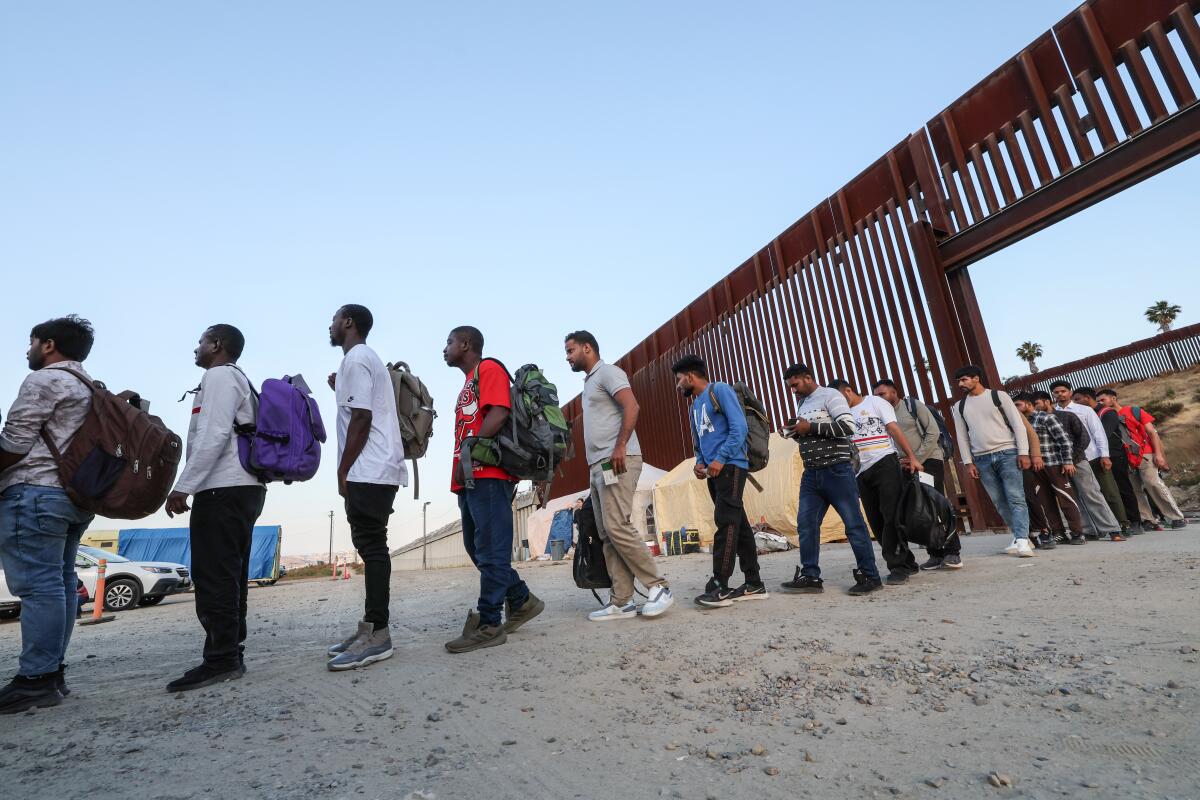 People wait in a line at the U.S.-Mexico border.