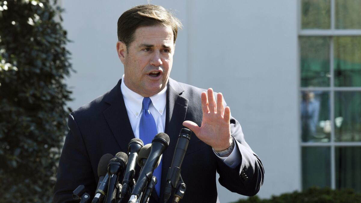 Arizona Gov. Doug Ducey talks to reporters outside the West Wing of the White House in Washington. Ducey is yanking a grant of up to $1 million from Nike amid a report that the athletic company pulled a flag-themed shoe from the market.