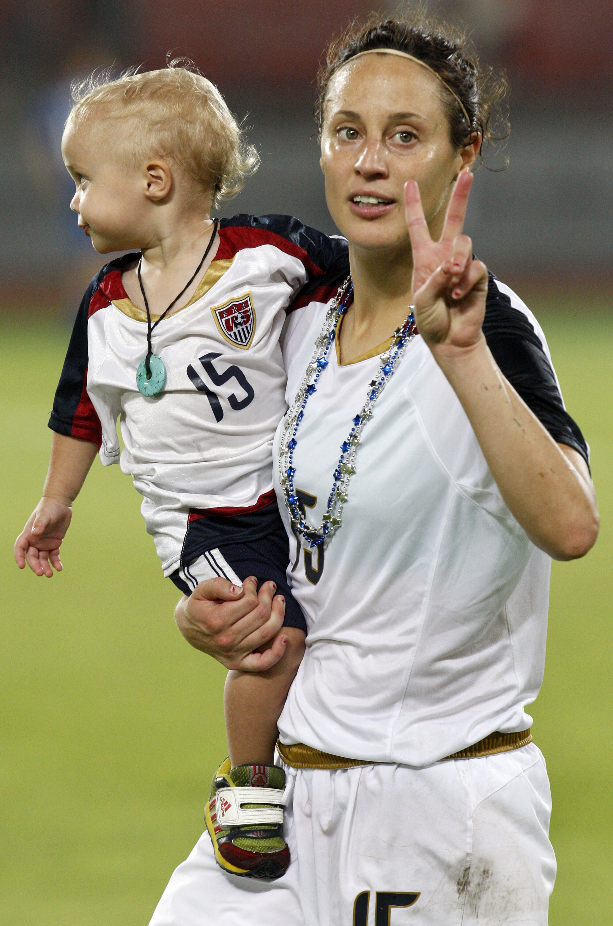 American Kate Markgraf carries her son, Keegan, after a 2008 Beijing Olympics women's semifinal soccer match against Japan