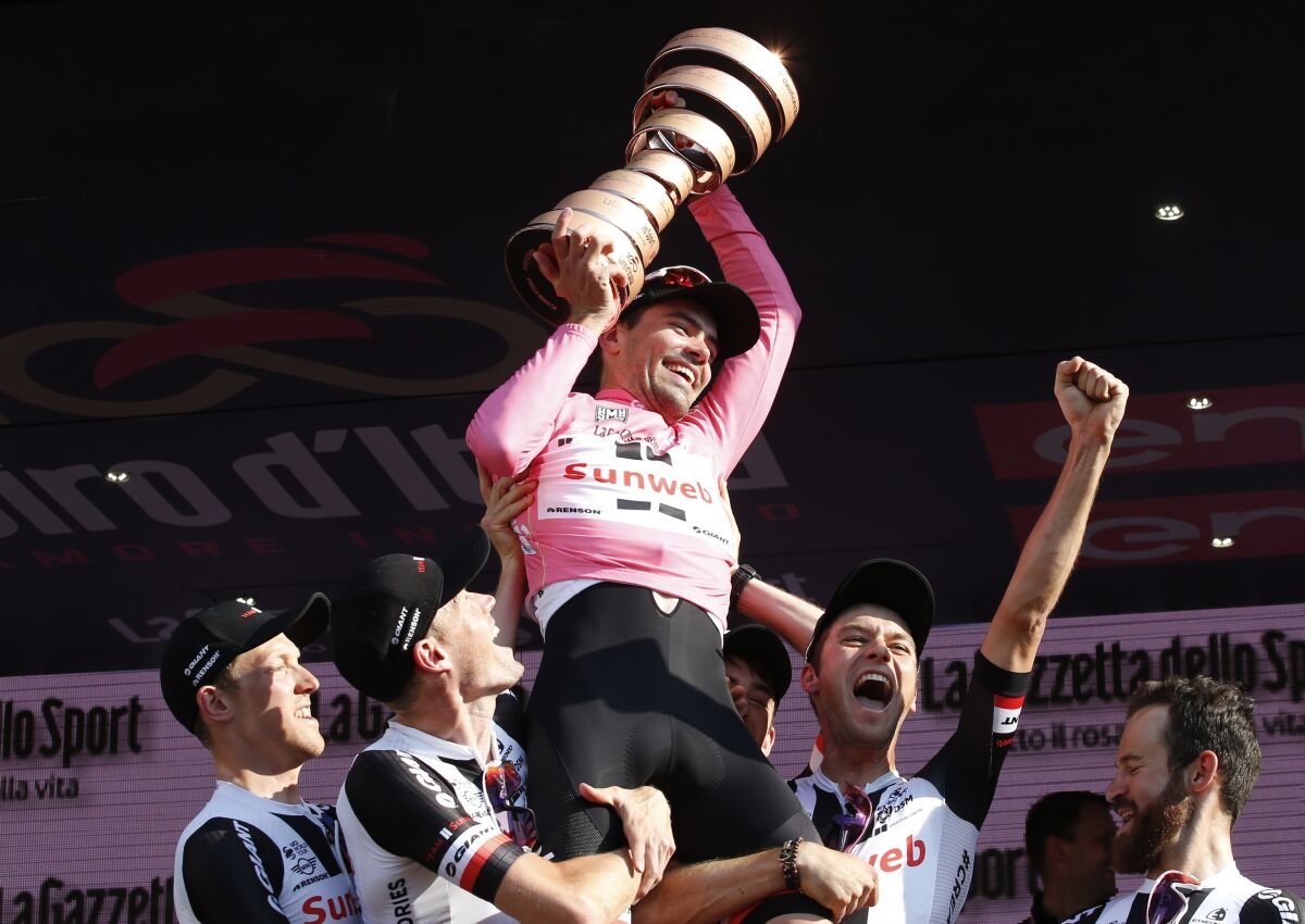 FILE- Tom Dumoulin, of the Netherlands, holds up the trophy as he celebrates with teammates after winning the Giro d'Italia, Tour of Italy cycling race on May 28, 2017, in Milan. The former Giro d'Italia champion announced Friday, June 3, 2022, that he will put an end to his career at the end of the season, saying that the sacrifices he makes no longer bring the results he wants. (AP Photo/Antonio Calanni, File)