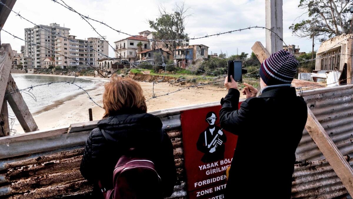 A man photographs the sealed-off beach resort of Varosha from behind a fortified fence in the city of Famagusta in the self-proclaimed Turkish Republic of Northern Cyprus on Jan. 6.