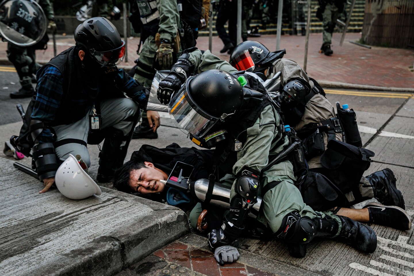 HONG KONG, CHINA -- SUNDAY, SEPTEMBER 29, 2019: Police officers in riot gear pin down a young protester as they confront demonstrators with tear gas, batons and shields and make mass arrests near the HK Police Headquarters as chaos grips the city leading up to ChinaÕs National Day this week, in Hong Kong, on Sept. 29, 2019. Despite Chief Executive Carrie LamÕs bowing to the demonstratorsÕ key demand Ð withdrawal of a controversial extradition bill, pro-democracy demonstrators are now calling for Lam to immediately meet the rest of their demands. This includes an independent inquiry into policeÕs use of force, amnesty for those arrested, a halt on the use of the word ÒRiotÓ when describing the rallies, and lastly, calls for universal suffrage for the people of Hong Kong. (Marcus Yam / Los Angeles Times)