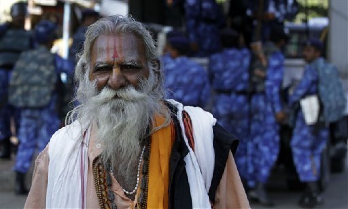 A Hindu holy man walks past as Rapid Action Force soldiers guard ahead of the Ayodhya verdict, in Ahmadabad, India, Wednesday, Sept. 29, 2010. The Allahabad High Court is scheduled to rule Thursday in the 60-year-old case on whether the site in the town of Ayodhya should be given to the Hindu community to build a temple to the god Rama or returned to the Muslim community to rebuild the 16th-century Babri Mosque that was razed by Hindu hard-liners in 1992. (AP Photo/Ajit Solanki)
