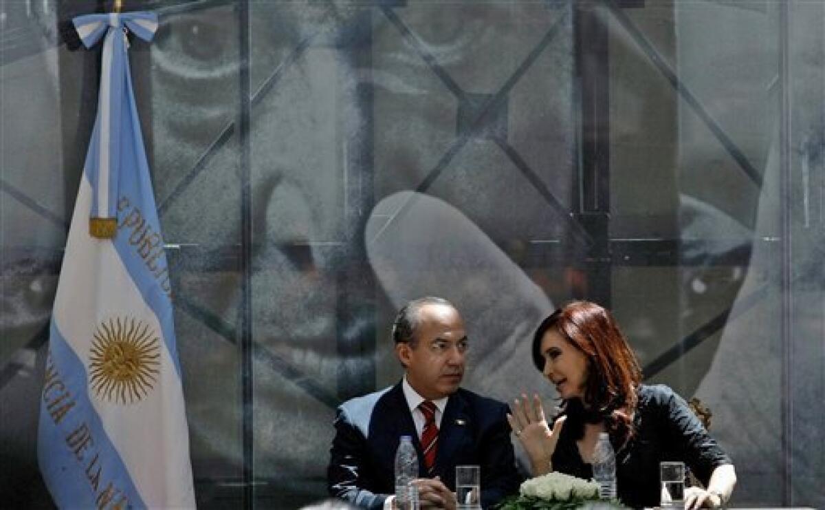 Mexico's President Felipe Calderon, left, and Argentina's President Cristina Fernandez talk back dropped by a photograph of Mexican artist David Alfaro Siqueiros, after inaugurating a mural painted by Siqueiros at the government house in Buenos Aires, Argentina, Friday, Dec. 3, 2010. The mural entitled "Ejercicio Plastico", has been placed at the future Museum of Political Arts, a former underground customs facility next to the government house. (AP Photo/Ivan Fernandez)