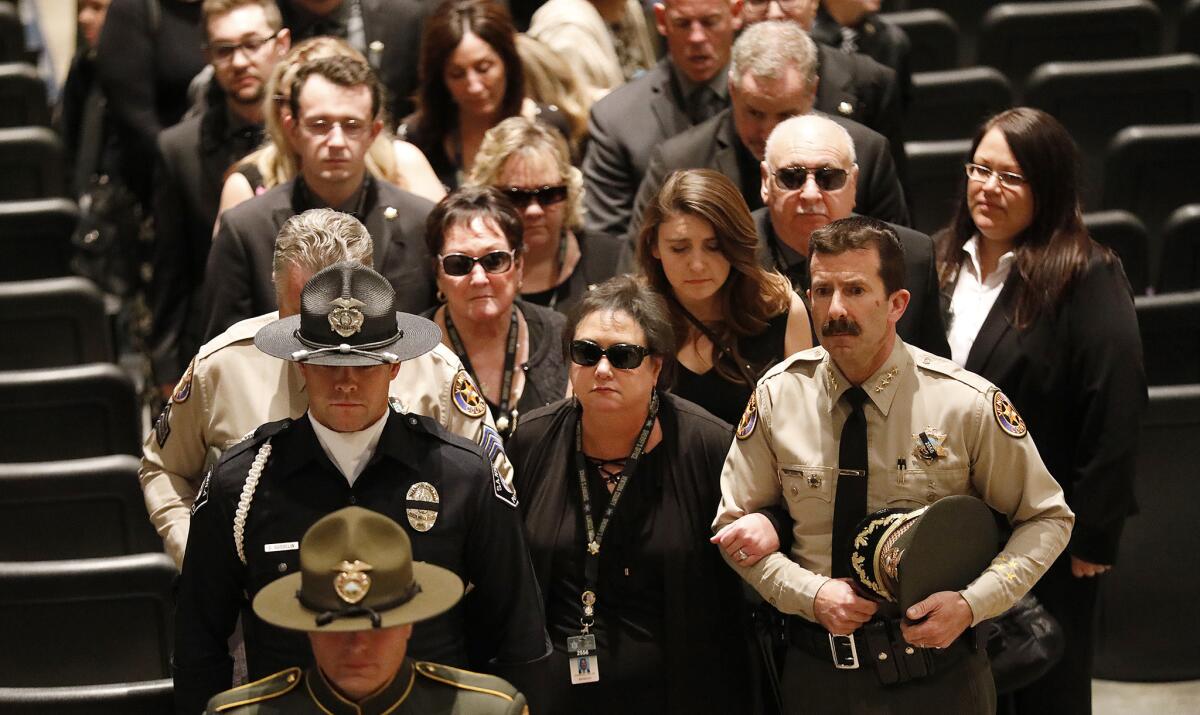 Karen Helus, wife of Ventura County Sheriff Sgt. Ron Helus, links arms with Ventura County Sheriff Bill Ayub, right, as they follow the casket of Sgt. Helus after a memorial service at Calvary Community Church in Westlake Village on Nov. 15.