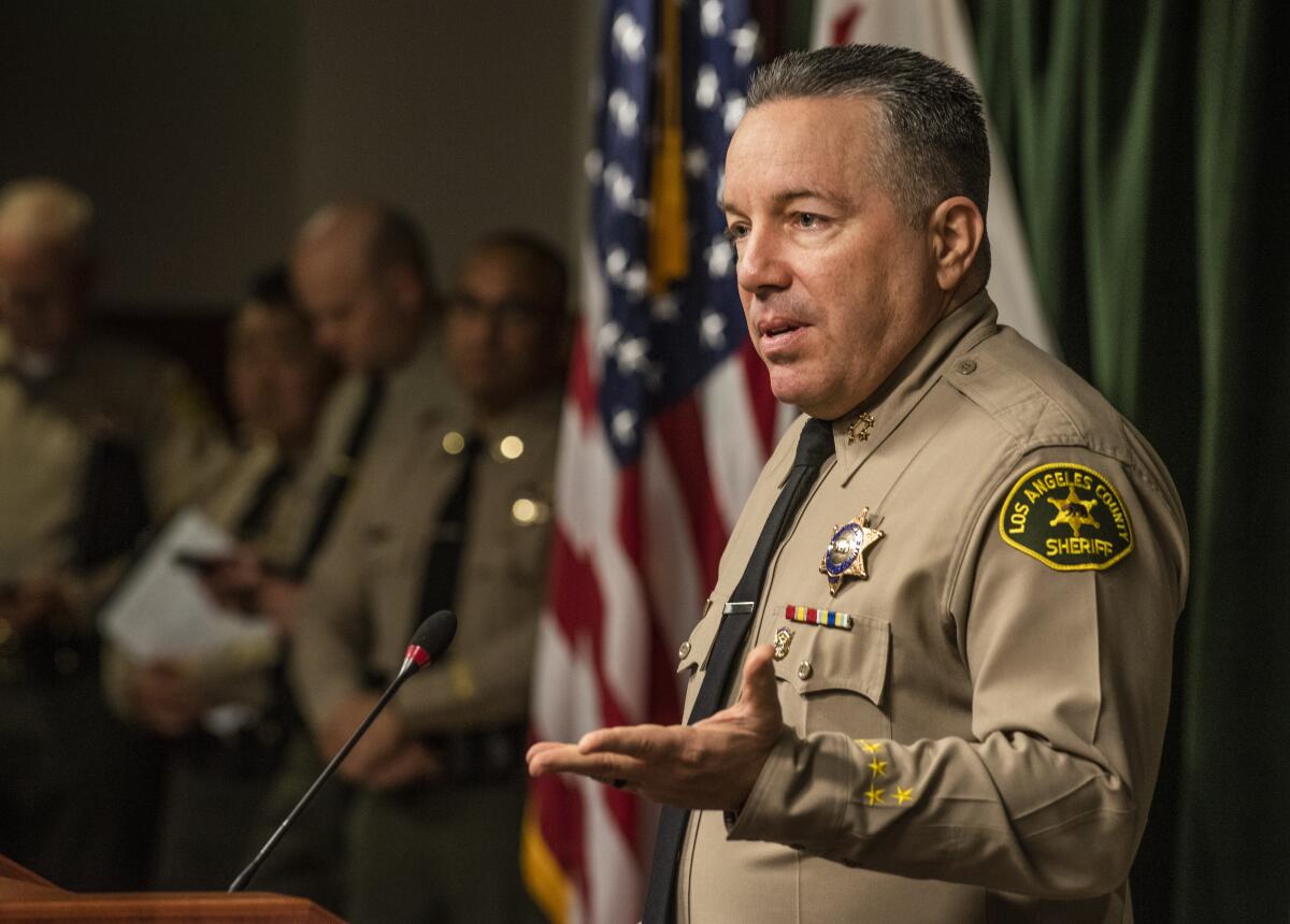 Sheriff Alex Villanueva, in front of a microphone, speaks to the media in March.