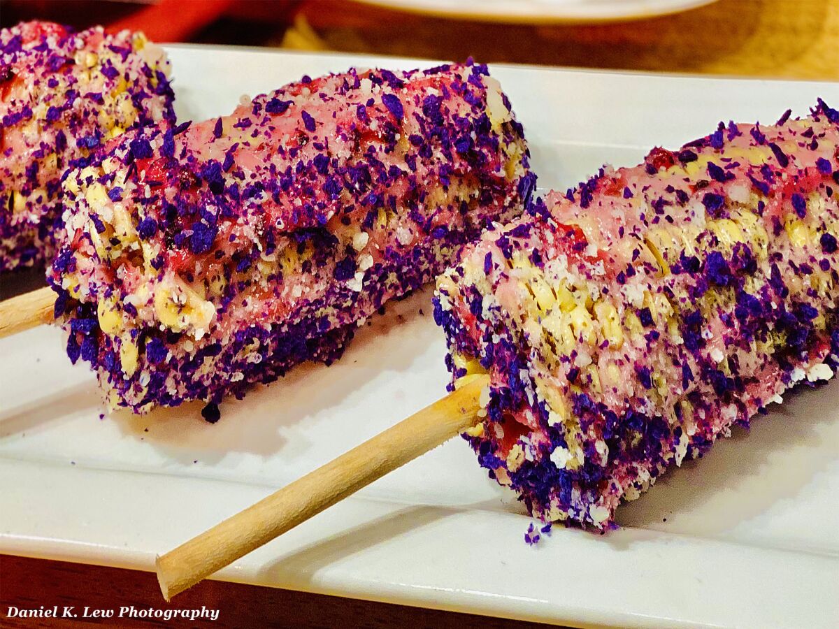 Elote (corn) rolled in boysenberry mayo topped with a boysenberry tortilla crumble and cotija cheese is among the unique foods offered during Knott's Boysenberry Festival, March 20-April 19, 2020 at Knott's Berry Farm theme park in Buena Park, California.