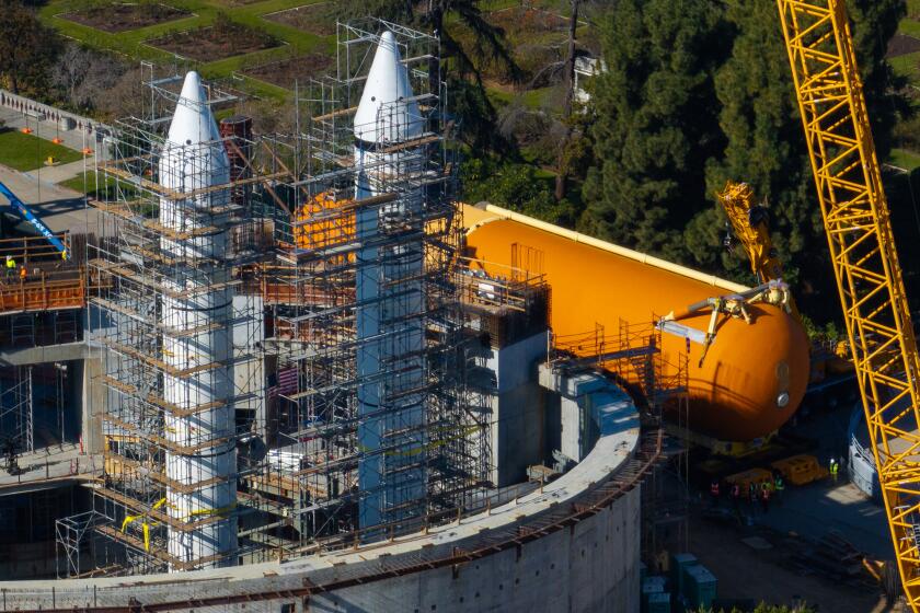 Los Angeles, CA -: The ET-94 Space Shuttle tank, right, arrives at site for installation alongside two 149-foot Solid Rocket Boosters, left, during the multi-phase Go for Stack process of creating the world's only authentic, 20-story, ready-to-launch space shuttle system display at the California Science Center's future Samuel Oschin Air and Space Center January 10. The enormous, orange ET-94 weighs 65,000 lbs., stands 154 feet top to bottom, has a diameter of 27.5 feet, and is the last remaining flight-qualified External Tank in existence. (Brian van der Brug / Los Angeles Times)