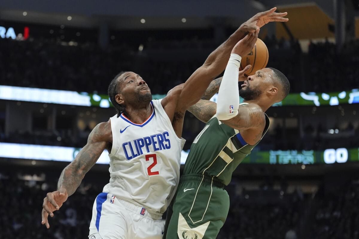 Clippers forward Kawhi Leonard tries to block a shot by Bucks guard Damian Lillard during the first half Monday night.