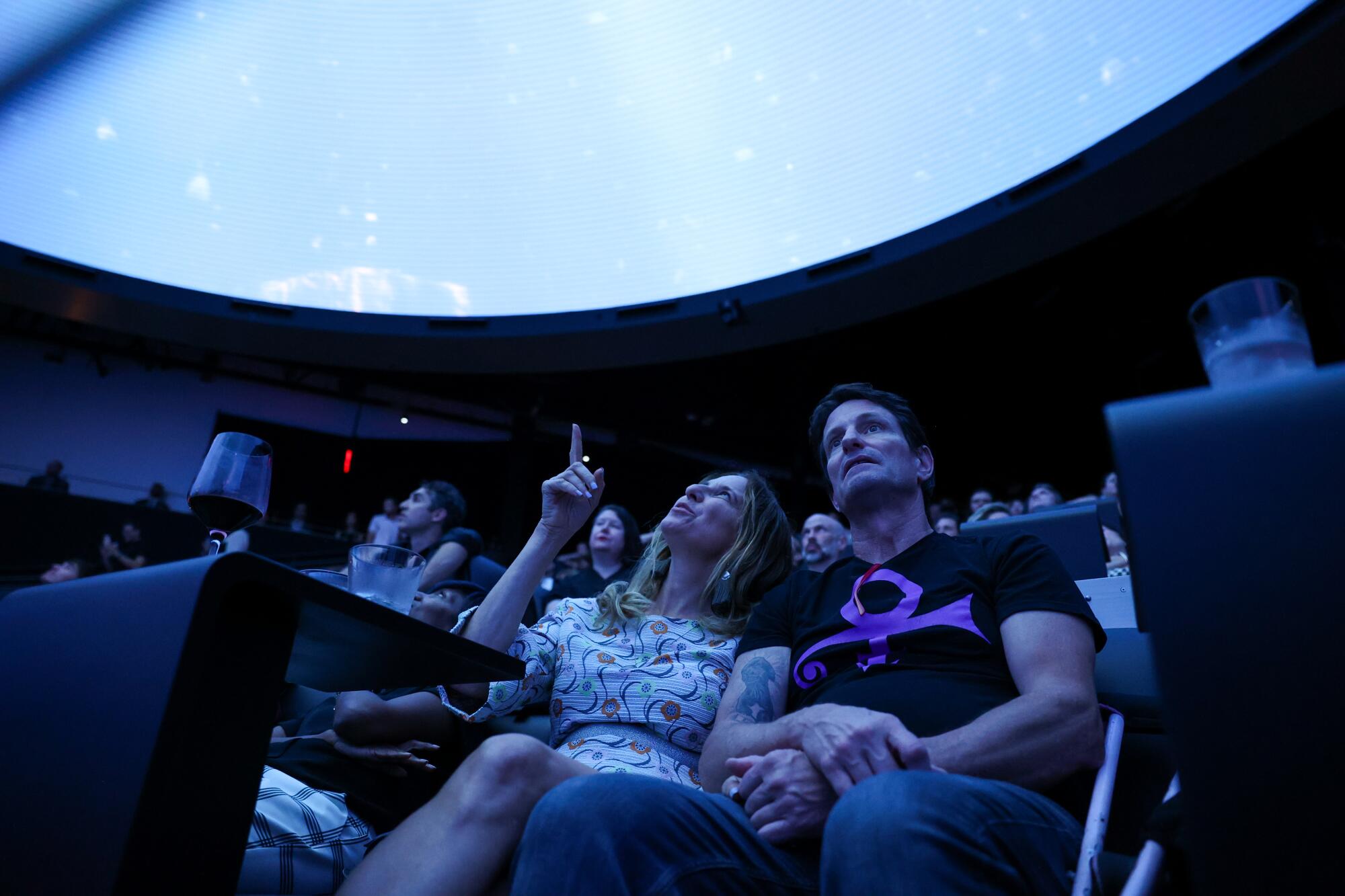 Two guests look up at an immersive screen. 