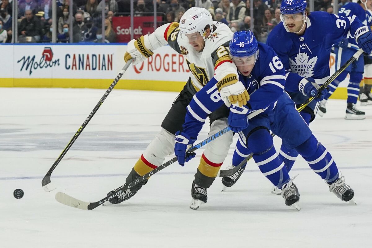 Vegas Golden Knights forward Mattias Janmark (26) and Toronto Maple Leafs forward Mitchell Marner (16) vie for possession of the puck during the first period of an NHL hockey game Tuesday, Nov. 2, 2021, in Toronto. (Evan Buhler/The Canadian Press via AP)