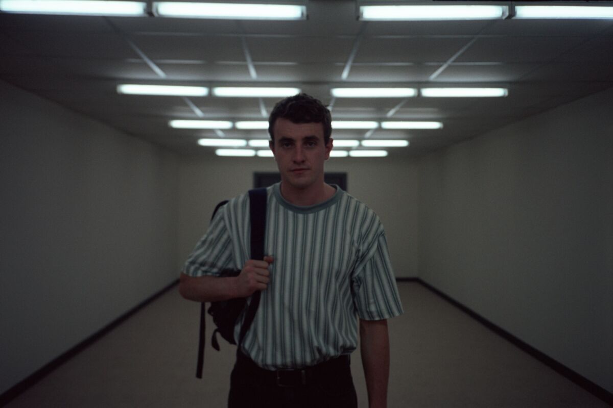 Paul Mescal, in a striped T-shirt, walks along a fluorescent-lighted hallway.