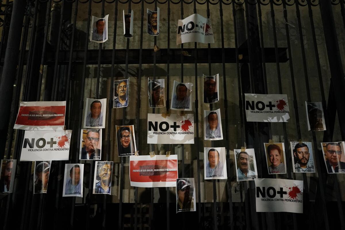 Photos of people's faces and "No+" signs are posted on a metal fence.