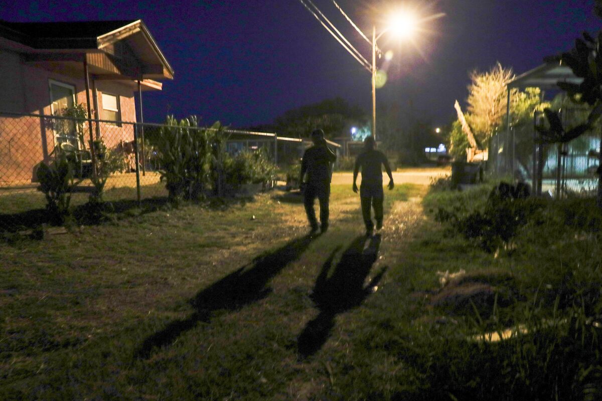 Two men suspected of crossing the border illegally search for a safe house in the early morning darkness in Colonia De La Cruz. After speaking briefly to a journalist, they turned around in apparent confusion and headed back down the alley.