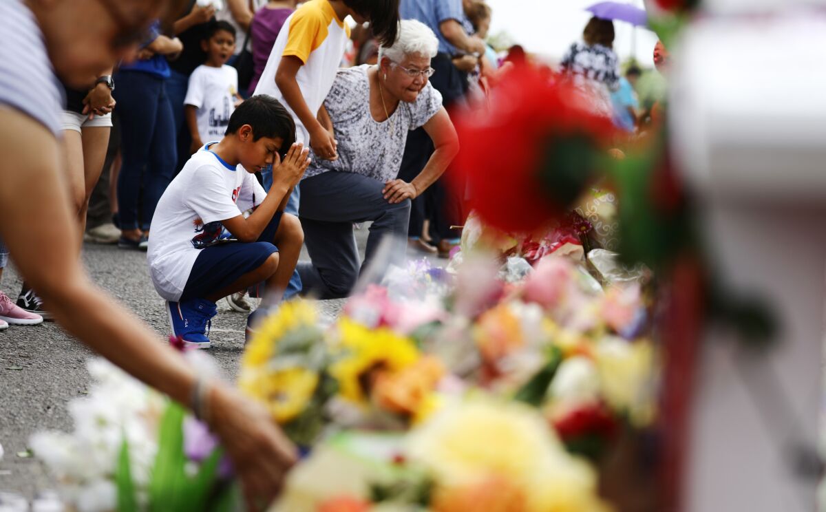 People visit a sidewalk memorial Tuesday for victims of the mass shooting in El Paso.