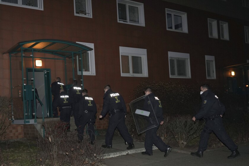 Federal police officers raid an apartment building in the Hohenschonhausen district, in Bremen, Germany, Wednesday, Dec. 8, 2021. German police conducted raids across the country to crack down on the alleged human trafficking of unskilled workers from outside the European Union. Federal police in Berlin tweeted that the raids started at 7 a.m. local time (0800GMT) on Wednesday. (Jorg Carstensen/dpa via AP)