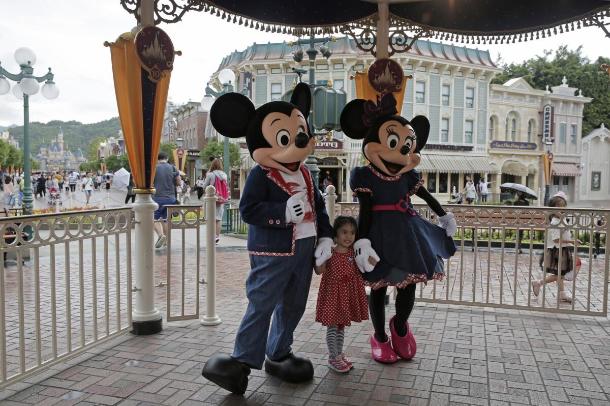 A girl poses with Mickey and Minnie Mouse at the Hong Kong Disneyland. The park is slated for a $1.4 billion expansion.
