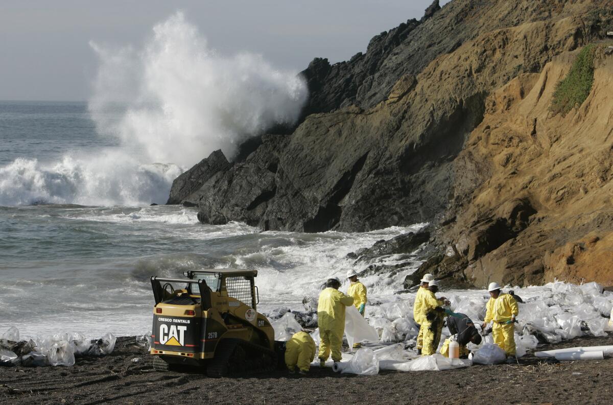Workers in protective gear on a beach with myriad plastic bags.