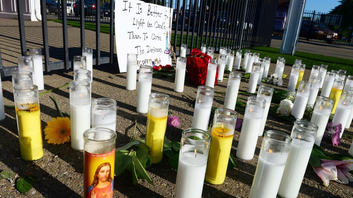 A memorial of candles and flowers grows at the scene of Tuesday's triple homicide shooting near Catholic Charities in downtown Fresno, Calif., on Wednesday, April 19, 2017.