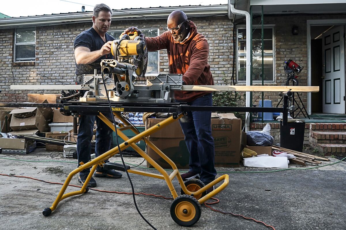 Jason Cameron, left, and Emmitt Smith use a power miter saw in "Secret Celebrity Renovation" on CBS.