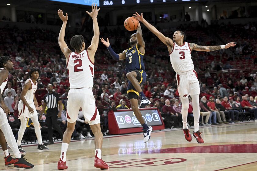 UNC Greensboro guard Kobe Langley (3) tries to drive past Arkansas defenders Trevon Brazile (2) and Nick Smith Jr. (3) during the first half of an NCAA college basketball game Tuesday, Dec. 6, 2022, in Fayetteville, Ark. (AP Photo/Michael Woods)