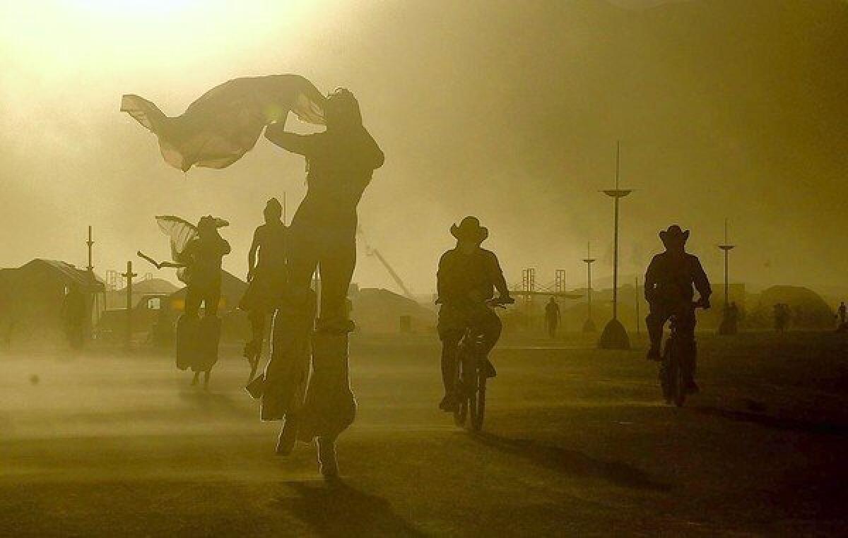 A daylong windstorm whips sand at Burning Man in Black Rock Desert, Nev., as participants take evening bike rides and strolls on stilts in August 2005.