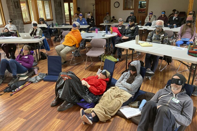 Personas que estudian para ser facilitadores de psilocibina están sentados con mascarillas mientras escuchan música durante un actividad experiencial en una sesión de capacitación de InnerTrek, cerca de Damascus, Oregon, el 2 de diciembre de 2022. (AP Foto/Andrew Selsky, Archivo)