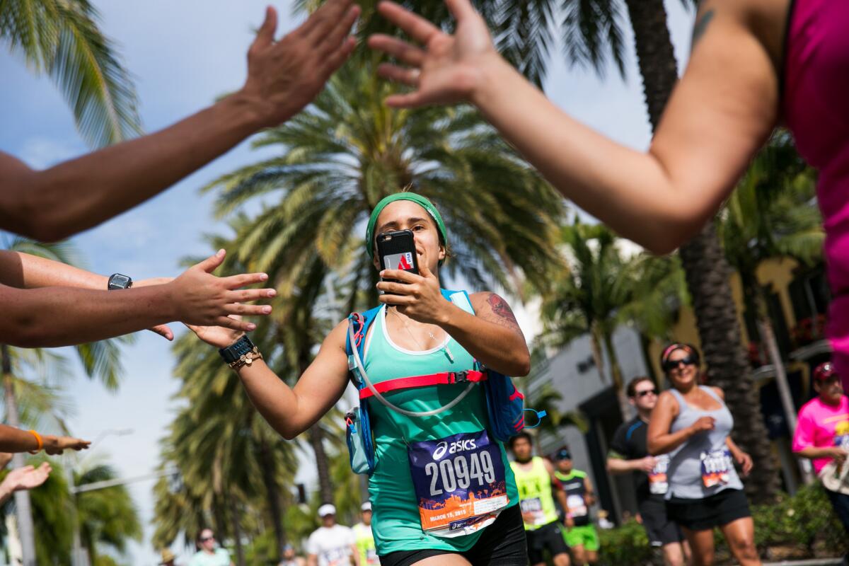 A runner in the Los Angeles Marathon records her high-fives with volunteers along Rodeo Drive in Beverly Hills on March 15.