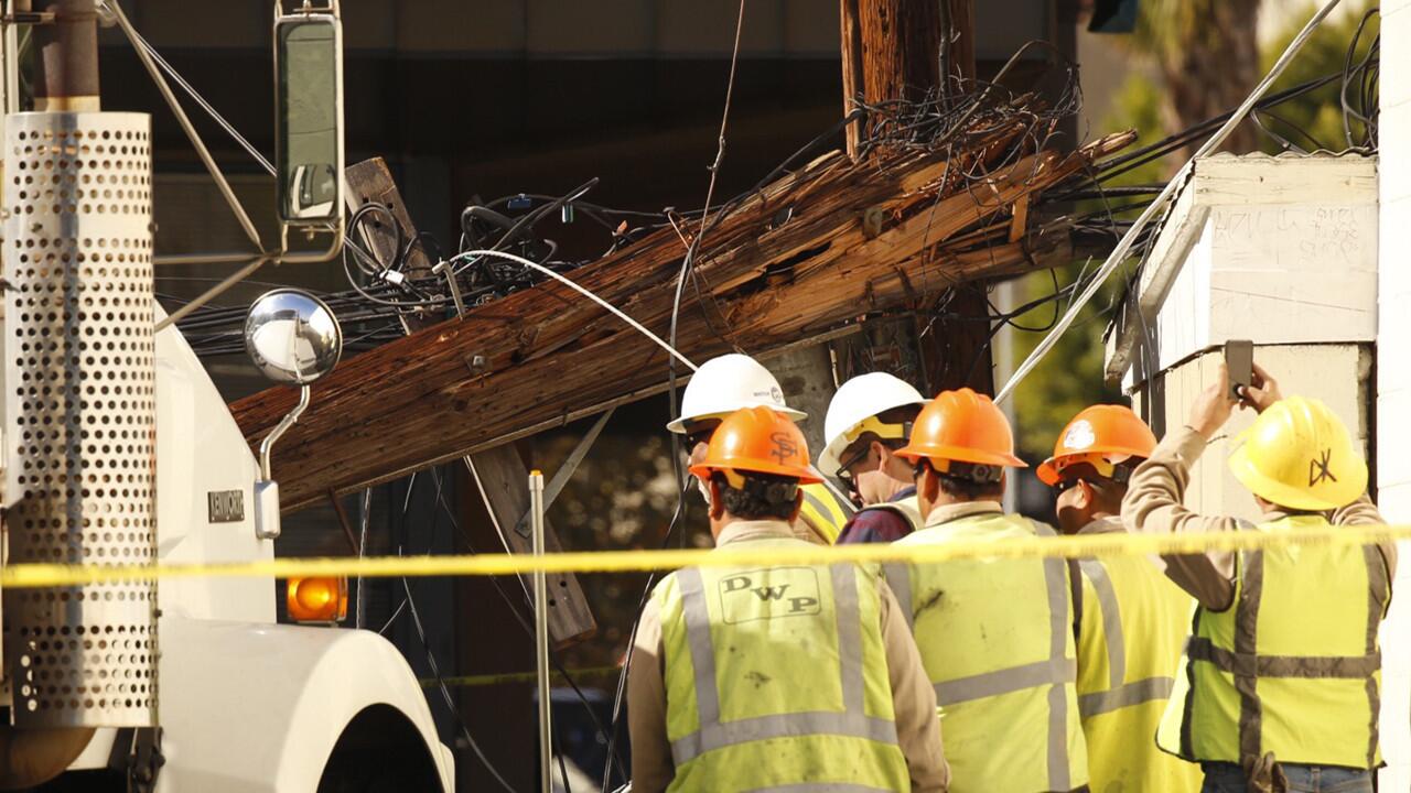DWP crews assess damage to a power pole that snapped in half behind a corner shopping mall at the corner of Wilshire and Highland in the mid Wilshire area.