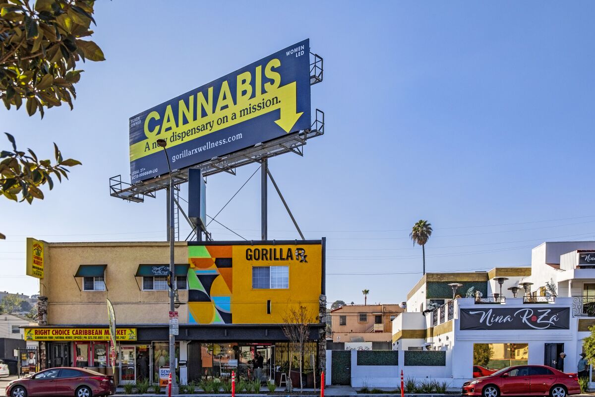 A dispensary exterior with a large cannabis billboard on the roof